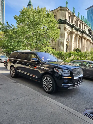 Black executive SUV parked near a historic building