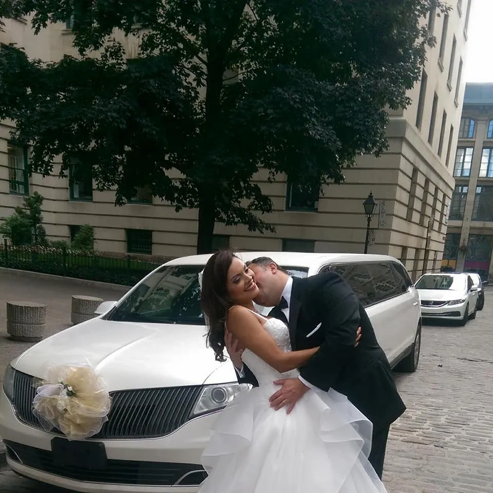 Bride and groom beside a white limousine